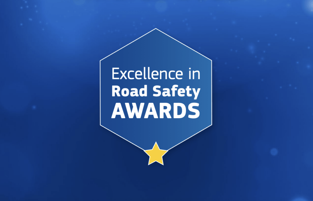 Blaues Banner mit der Aufschrift „Excellence in Road Safety Awards“ in einem sechseckigen Rahmen, darunter ein gelber Stern.